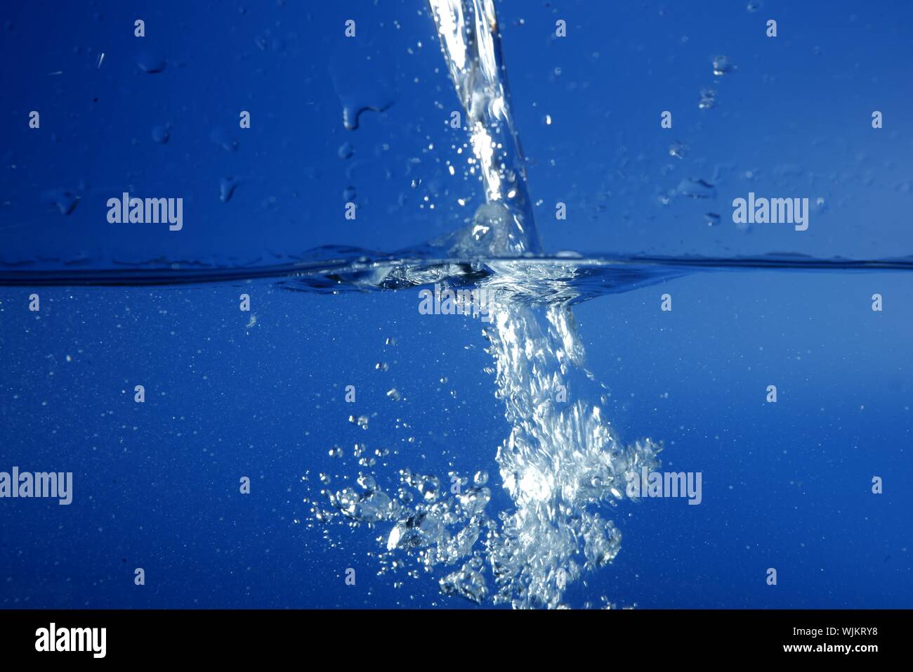 Blue water falling like splash close up macro side view Stock Photo - Alamy
