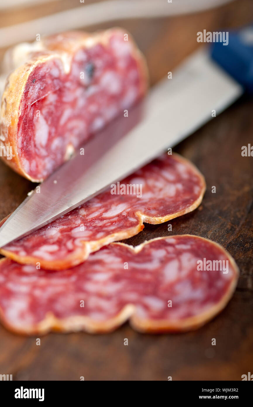 slicing italian salame pressato pressed over old wood table Stock Photo