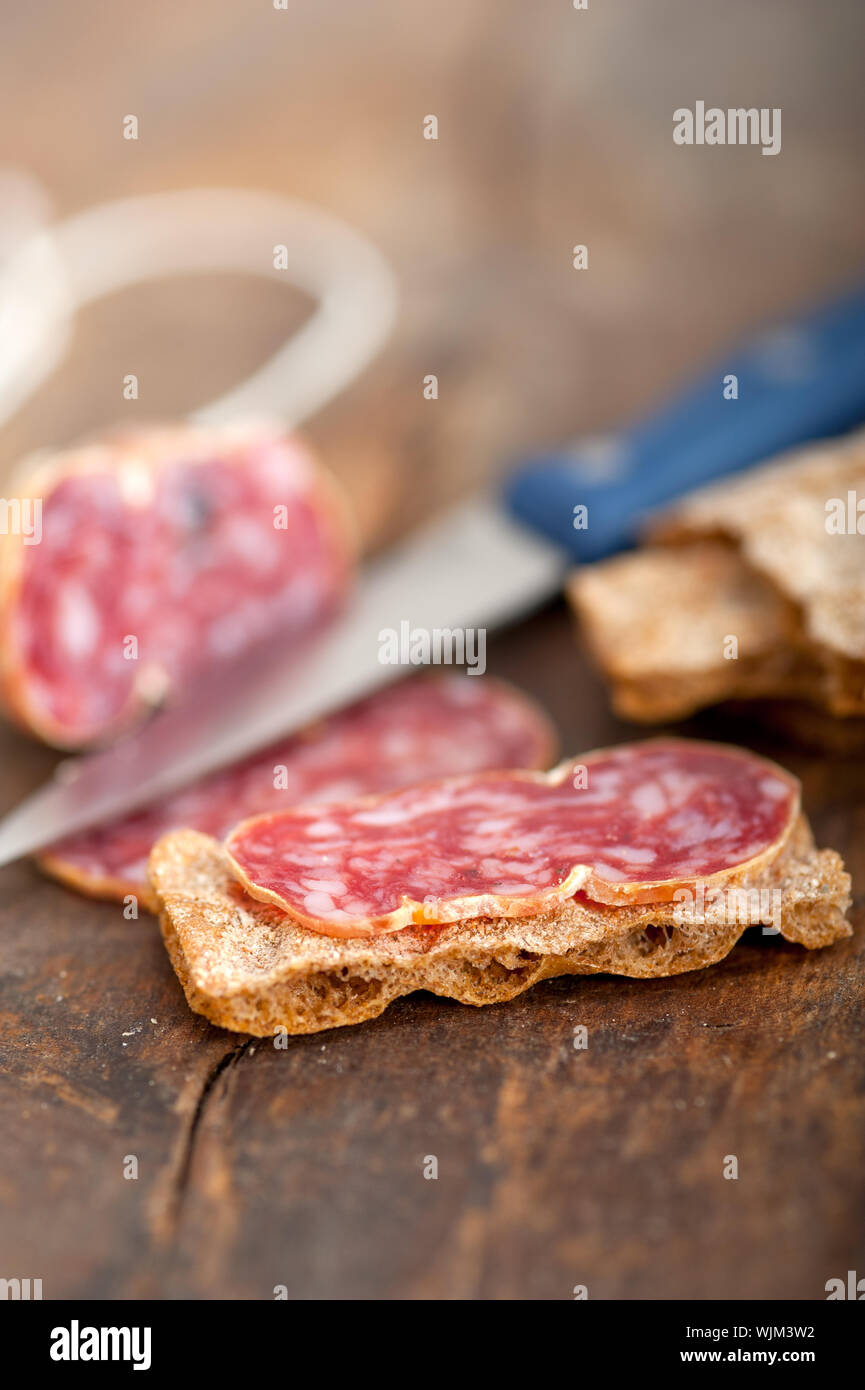 slicing italian salame pressato pressed over old wood table Stock Photo