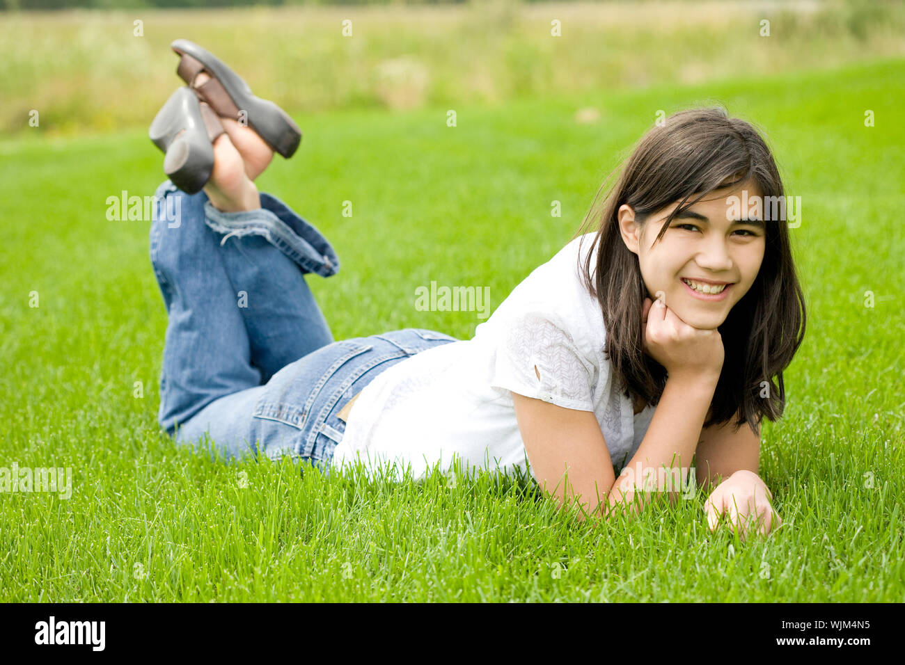 beautiful teen girl relaxing on lush green grass Stock Photo - Alamy