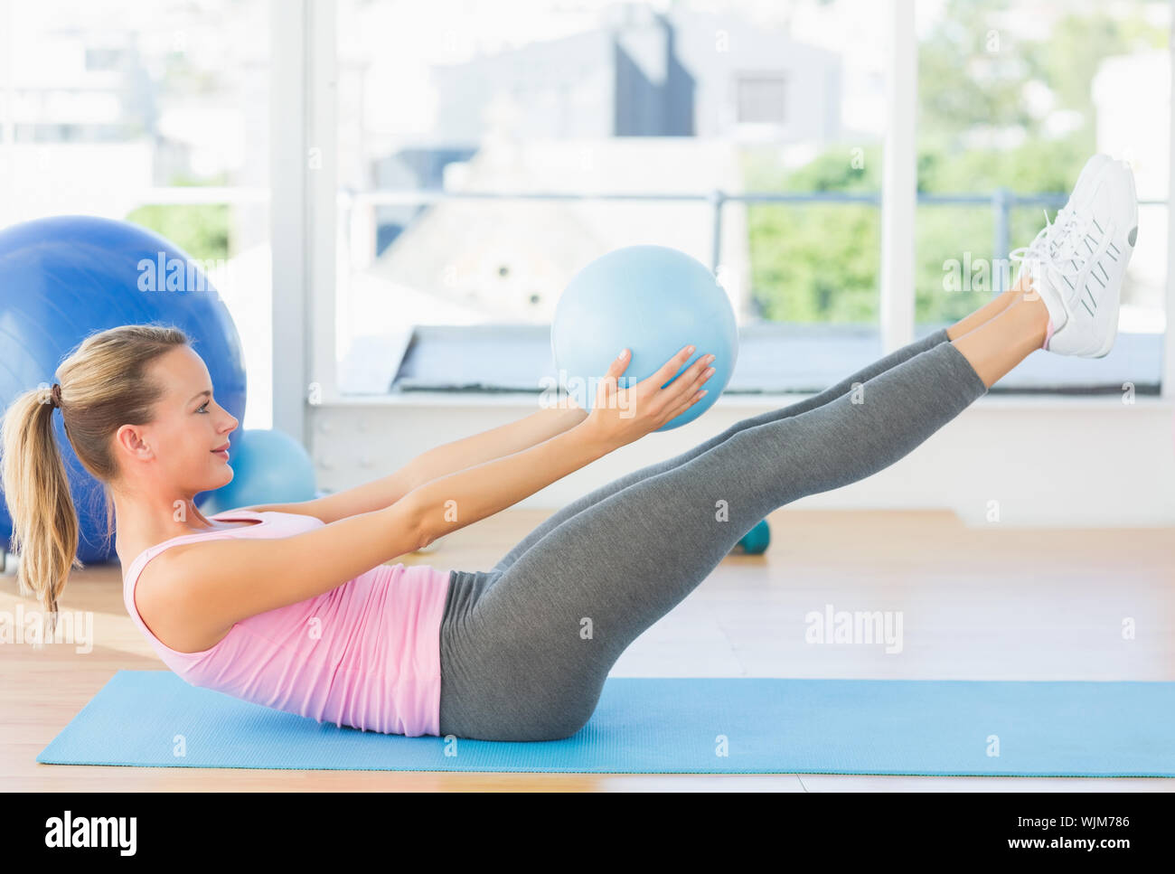 Full length side view of a sporty young woman stretching body in ...