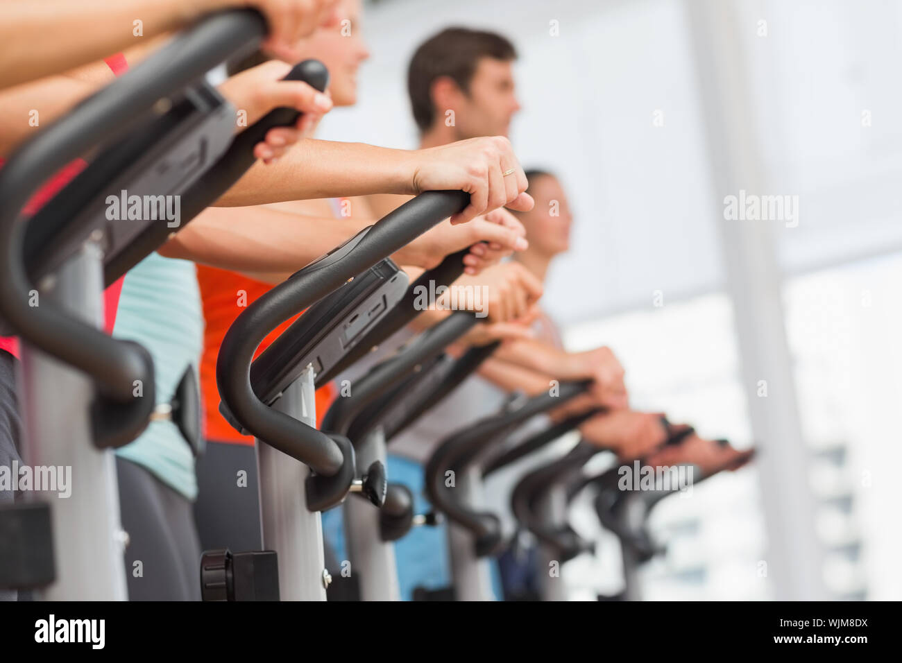 Side view of fit young people working out at spinning class in gym ...
