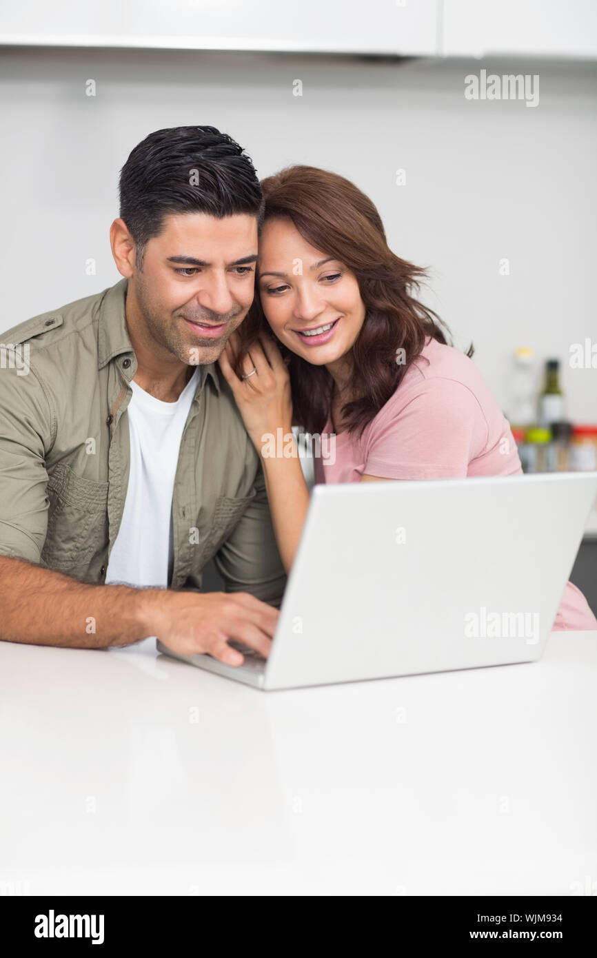 Happy couple using laptop in the kitchen at home Stock Photo - Alamy