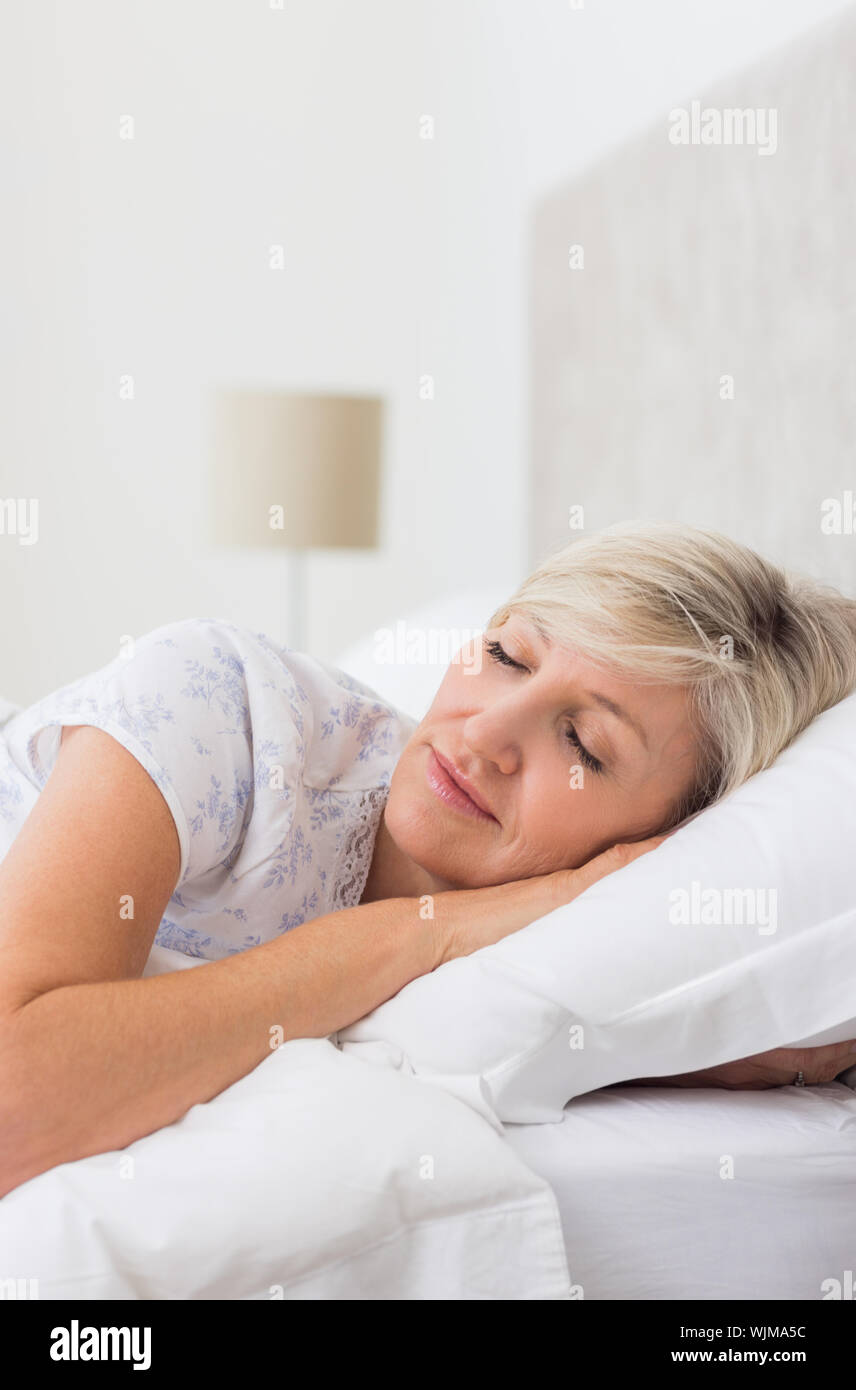 Pretty mature woman sleeping with eyes closed in the bed Stock Photo