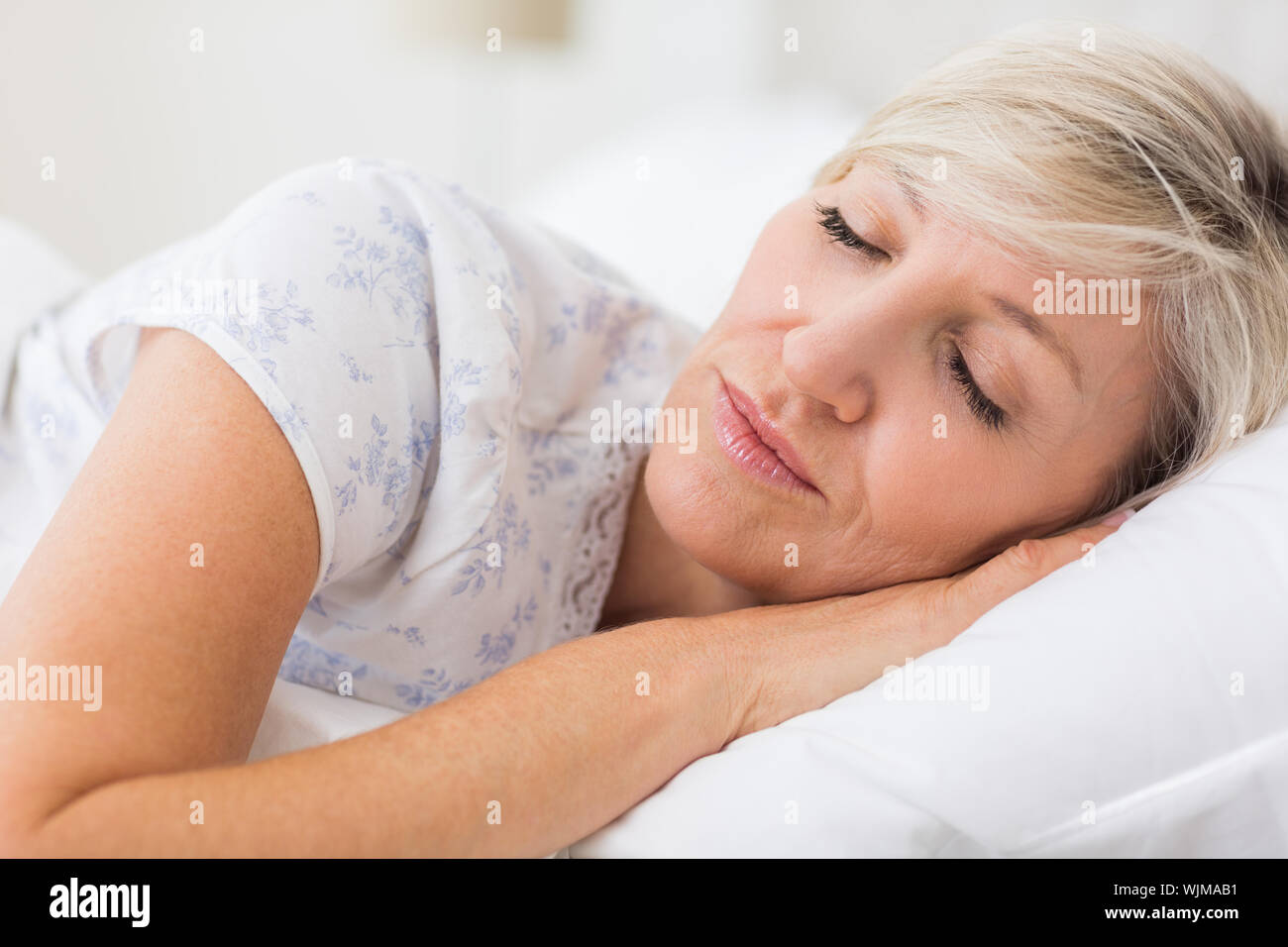 Pretty mature woman sleeping with eyes closed in the bed Stock Photo