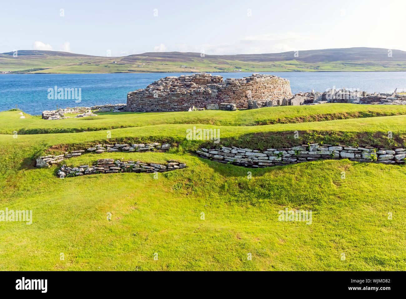 Broch of Gurness flanked by earth banks reinforced by stone. The broch village ruins surround it. Stock Photo