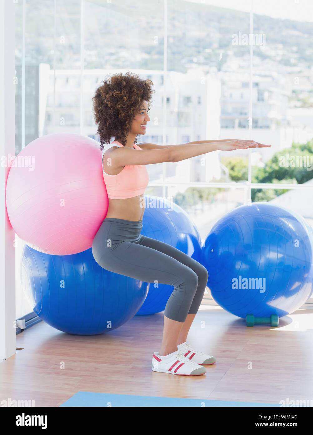 Side view of a sporty young woman with exercise ball in the fitness ...