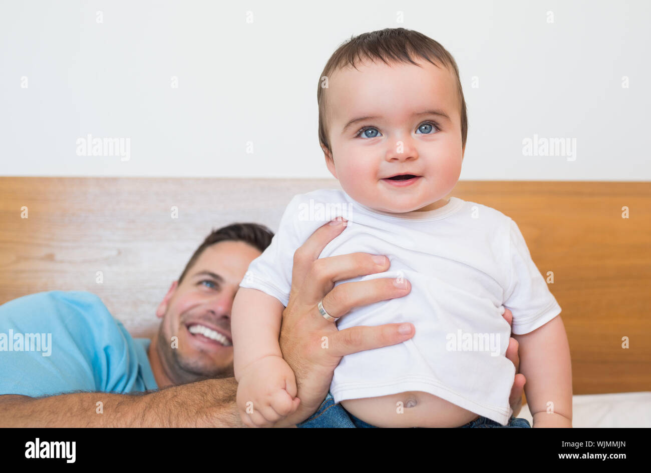 Happy cute baby boy with father in bed Stock Photo Alamy