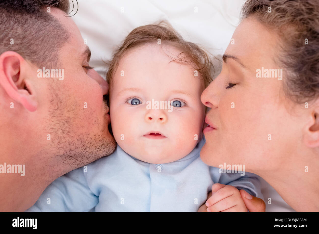 High angle of loving parents kissing baby boy in bed Stock Photo Alamy