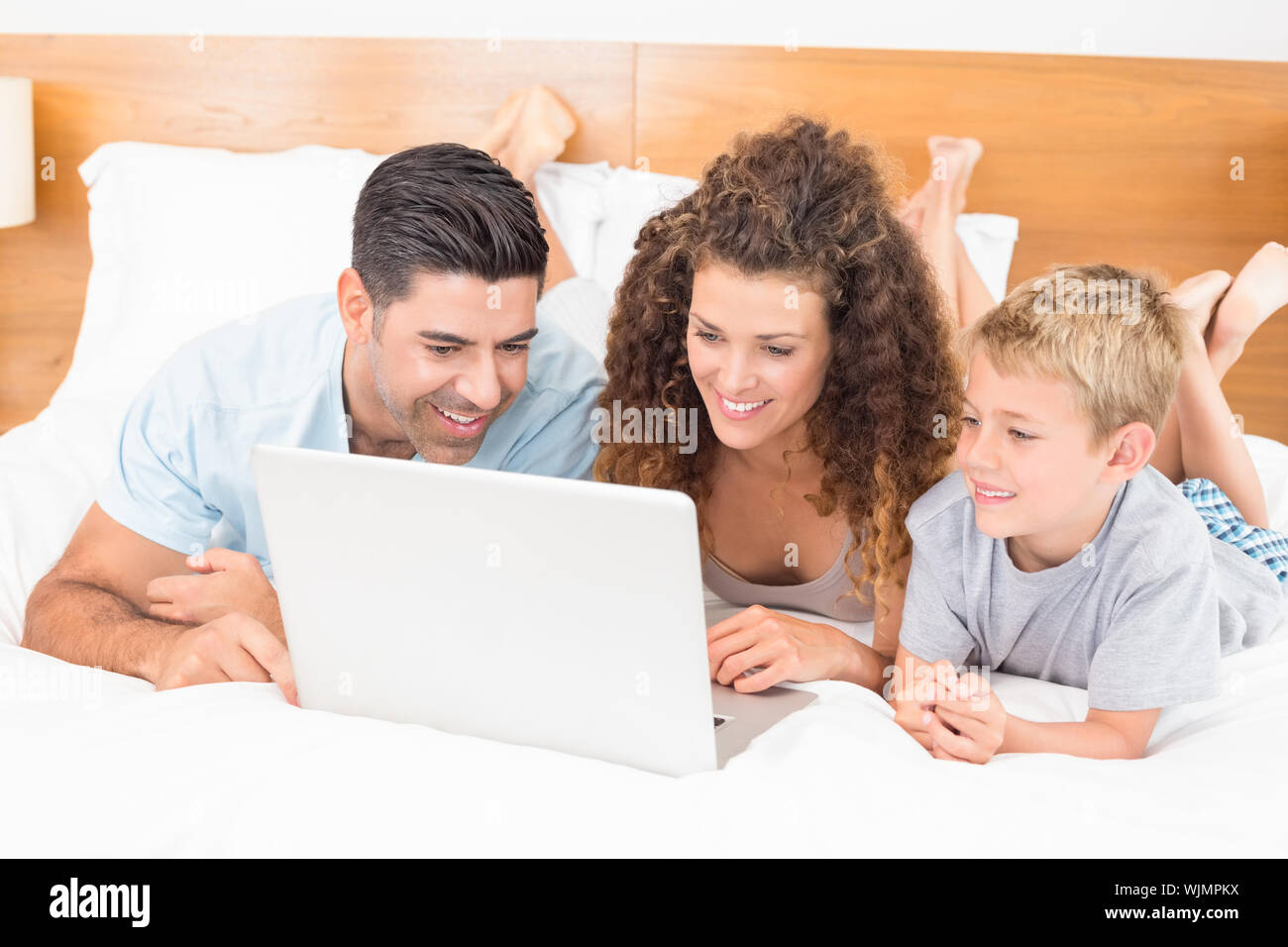 Happy family using laptop together on bed at home in bedroom Stock ...
