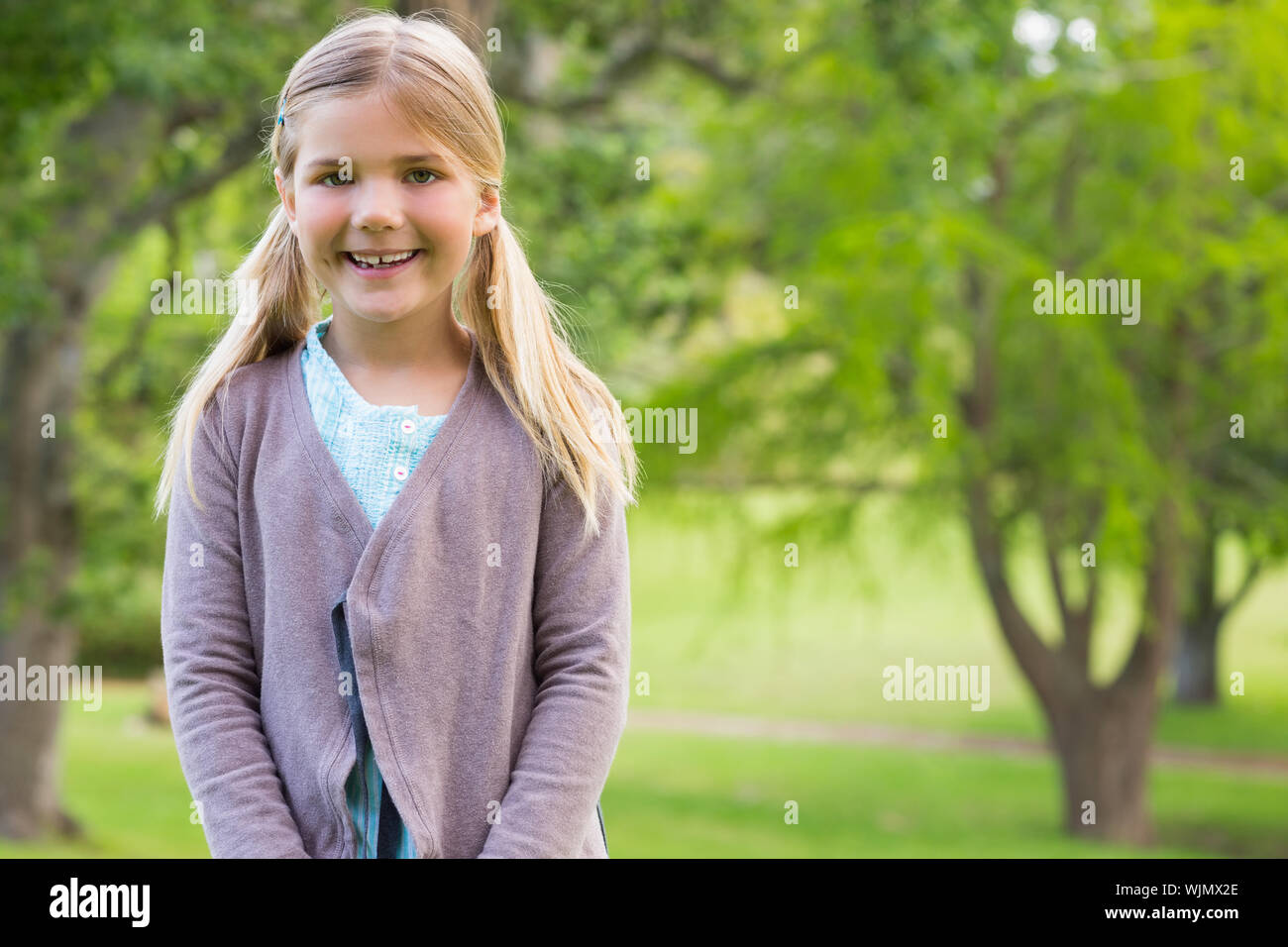 Portrait of a cute smiling young girl standing at the park Stock Photo ...