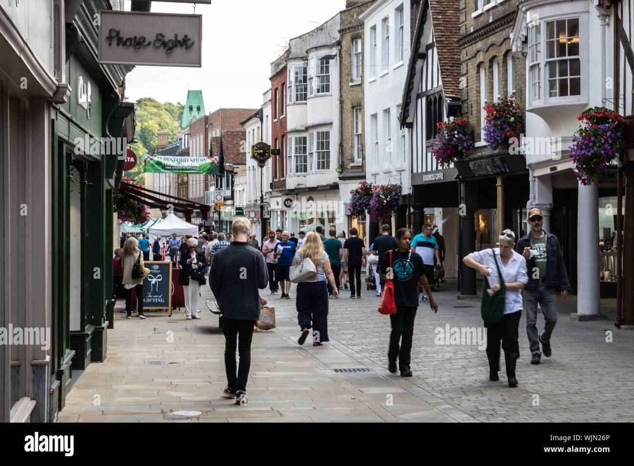 Winchester, Hampshire, UK Shoppers walking through Winchester High street passed various shops on a busy day for consumers Stock Photo