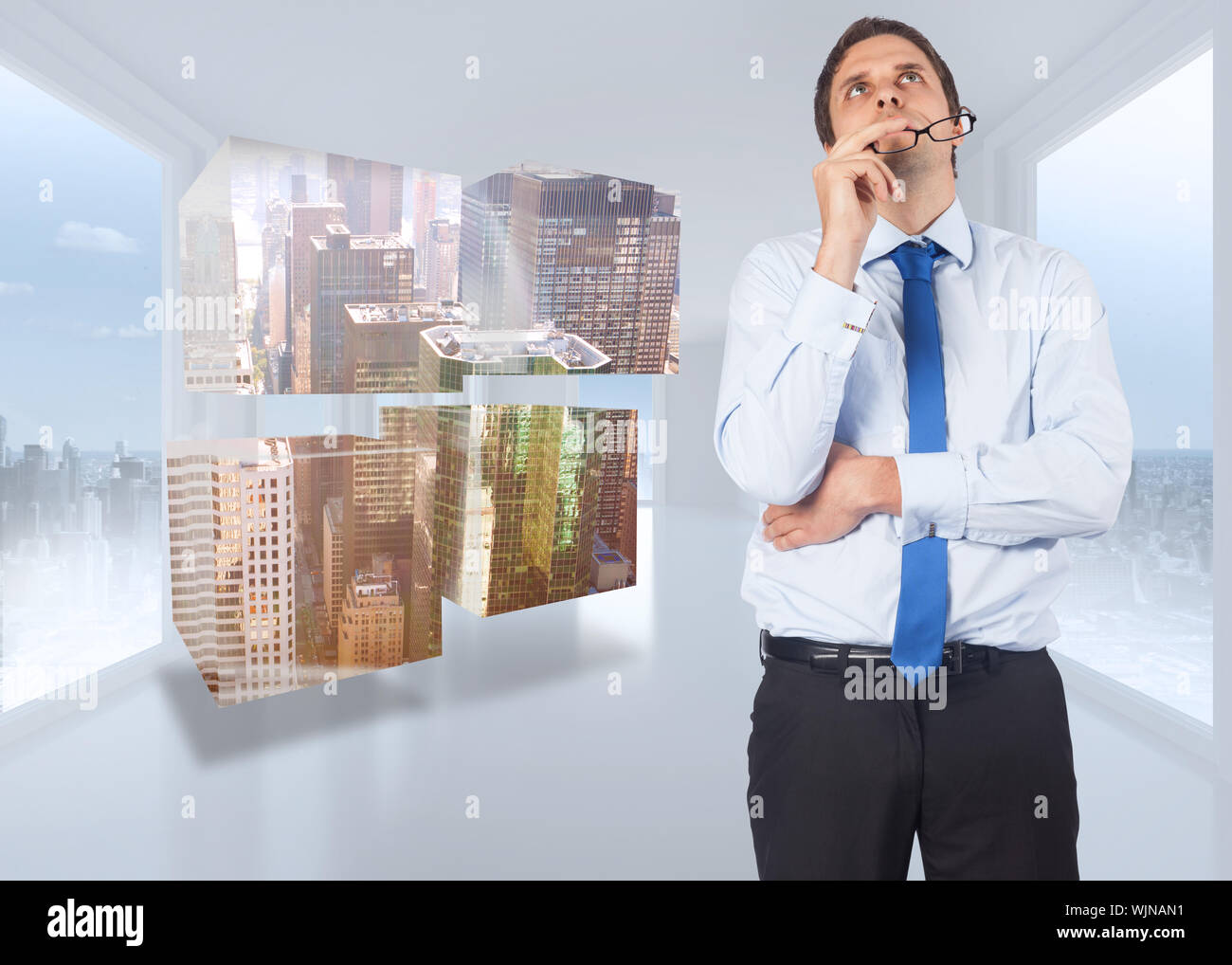 Thinking businessman biting glasses against bright white hall with windows Stock Photo