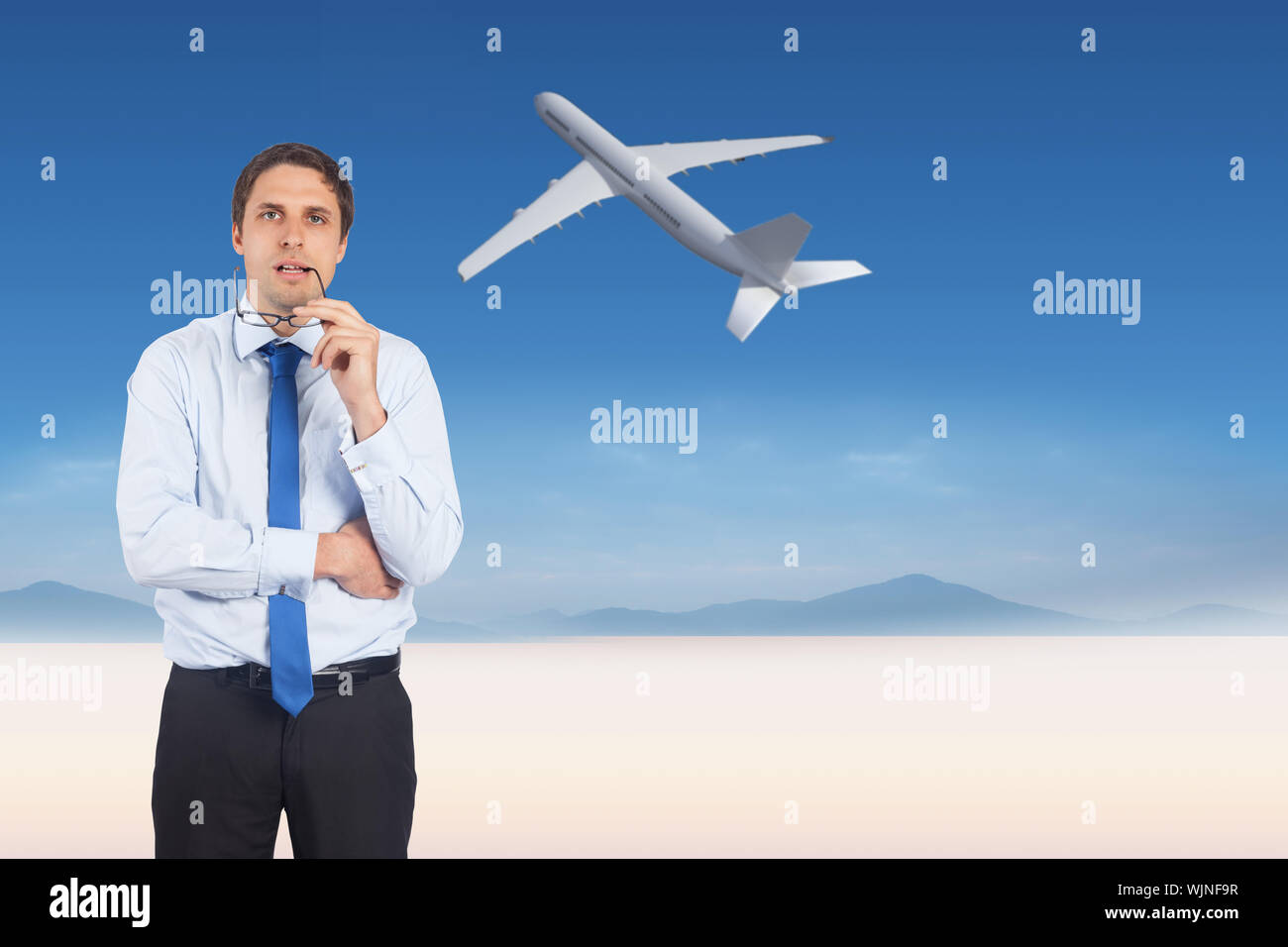 Thinking businessman biting glasses against serene landscape Stock Photo