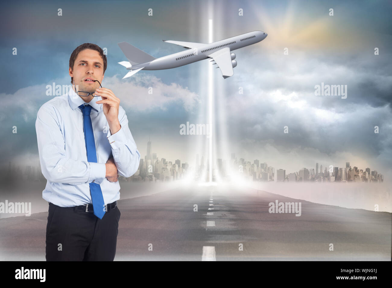 Thinking businessman biting glasses against open road Stock Photo
