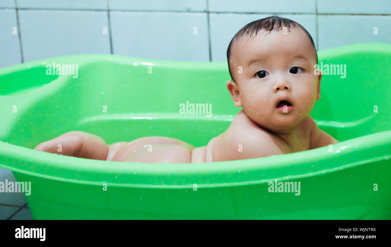 Cute Wet Baby In Green Plastic Bathtub Stock Photo