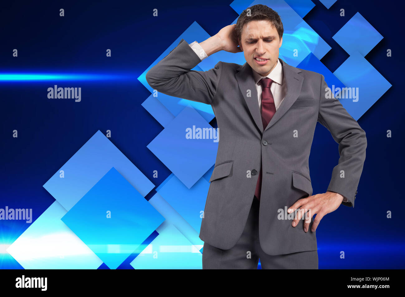 Thinking businessman scratching head against blue cube pattern Stock Photo