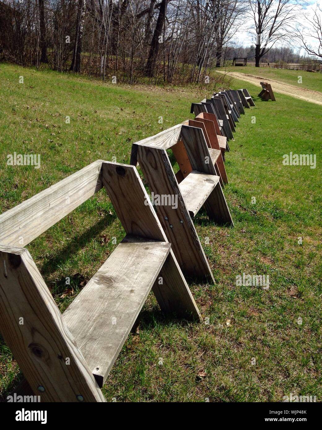 Row Of Wooden Benches On Grassy Field At Parka Stock Photo