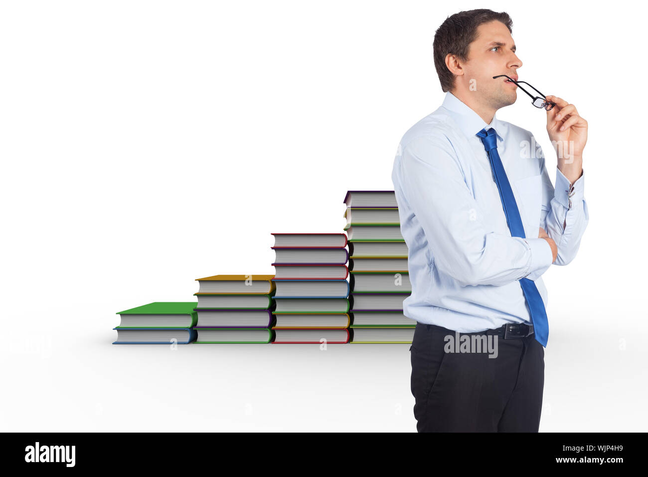 Thinking businessman biting glasses against steps made from books Stock Photo