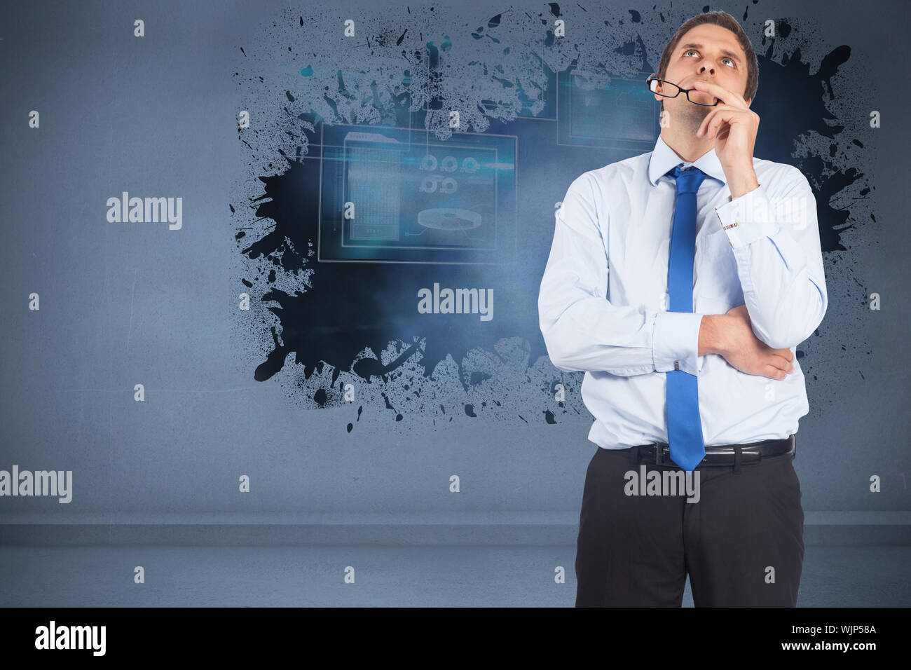 Thinking businessman biting glasses against splash showing technology interface Stock Photo