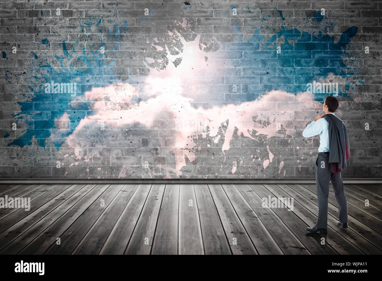 Businessman holding his jacket against splash on wall revealing clouds Stock Photo