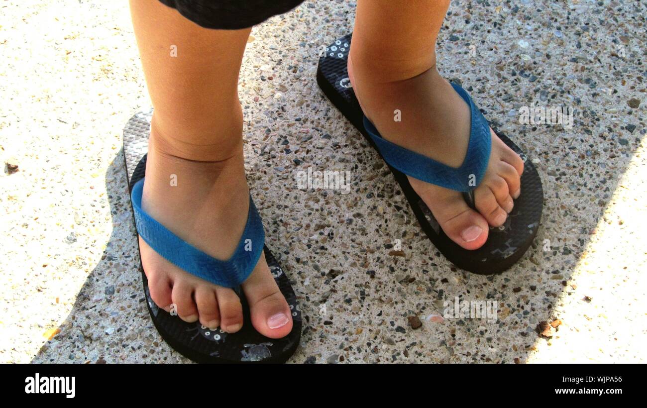 Low Section Of Boy Wearing Flip-flop Standing On Street Stock Photo - Alamy