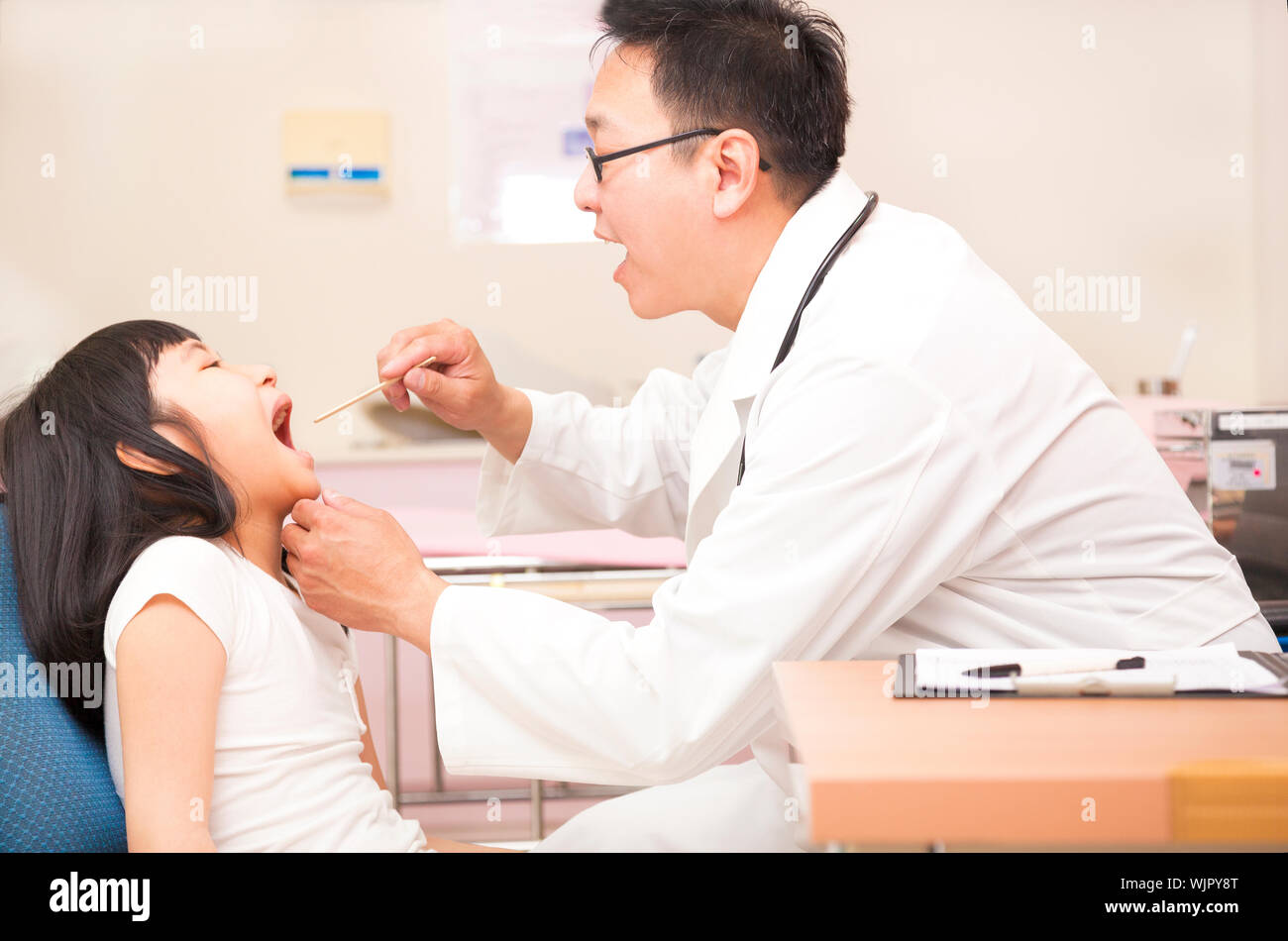 Little girl having throat examination with tongue depressor Stock Photo