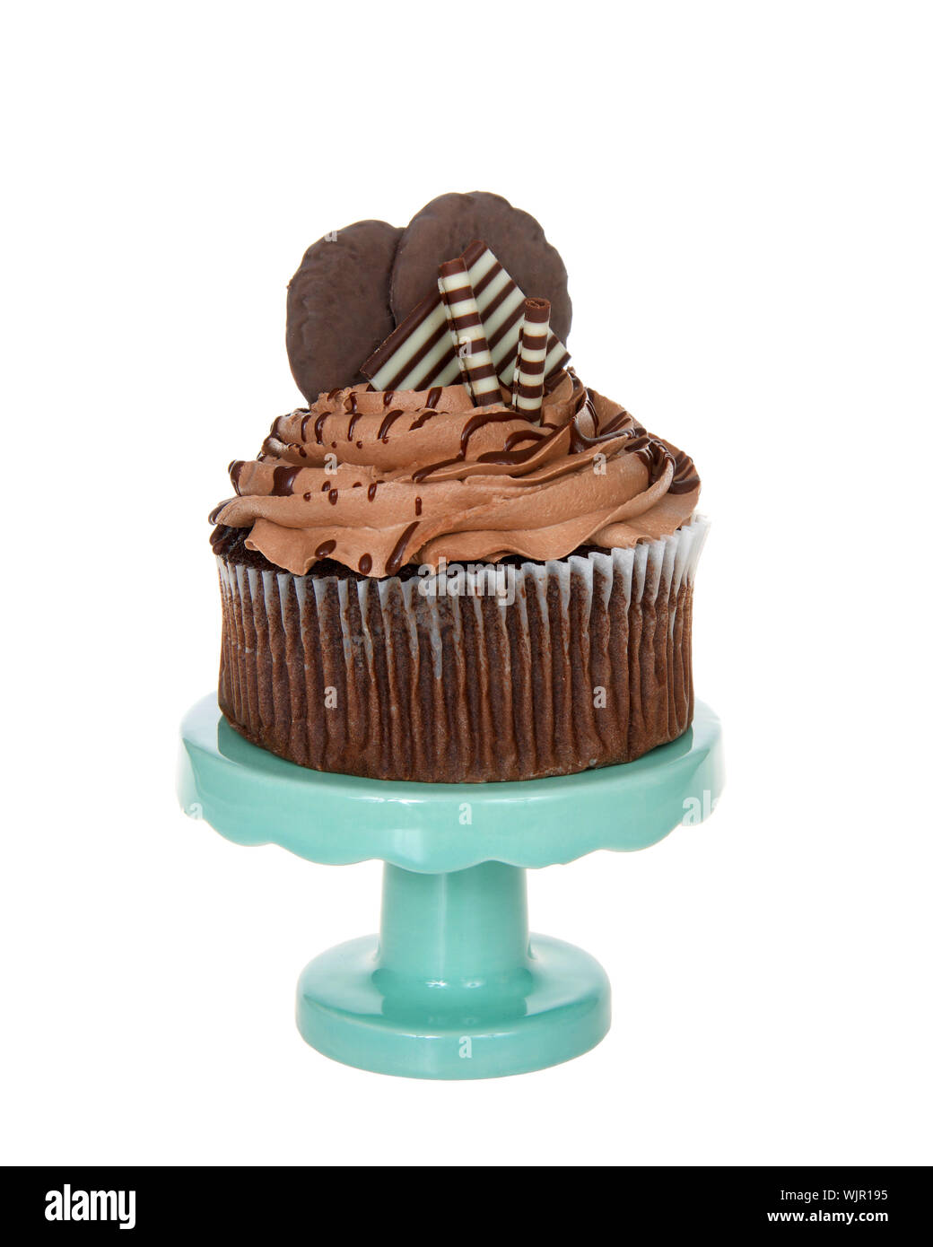 Giant chocolate cup cake with choc frosting, candy and cookies embellishing sitting on a teal green pedestal isolated on white. Stock Photo