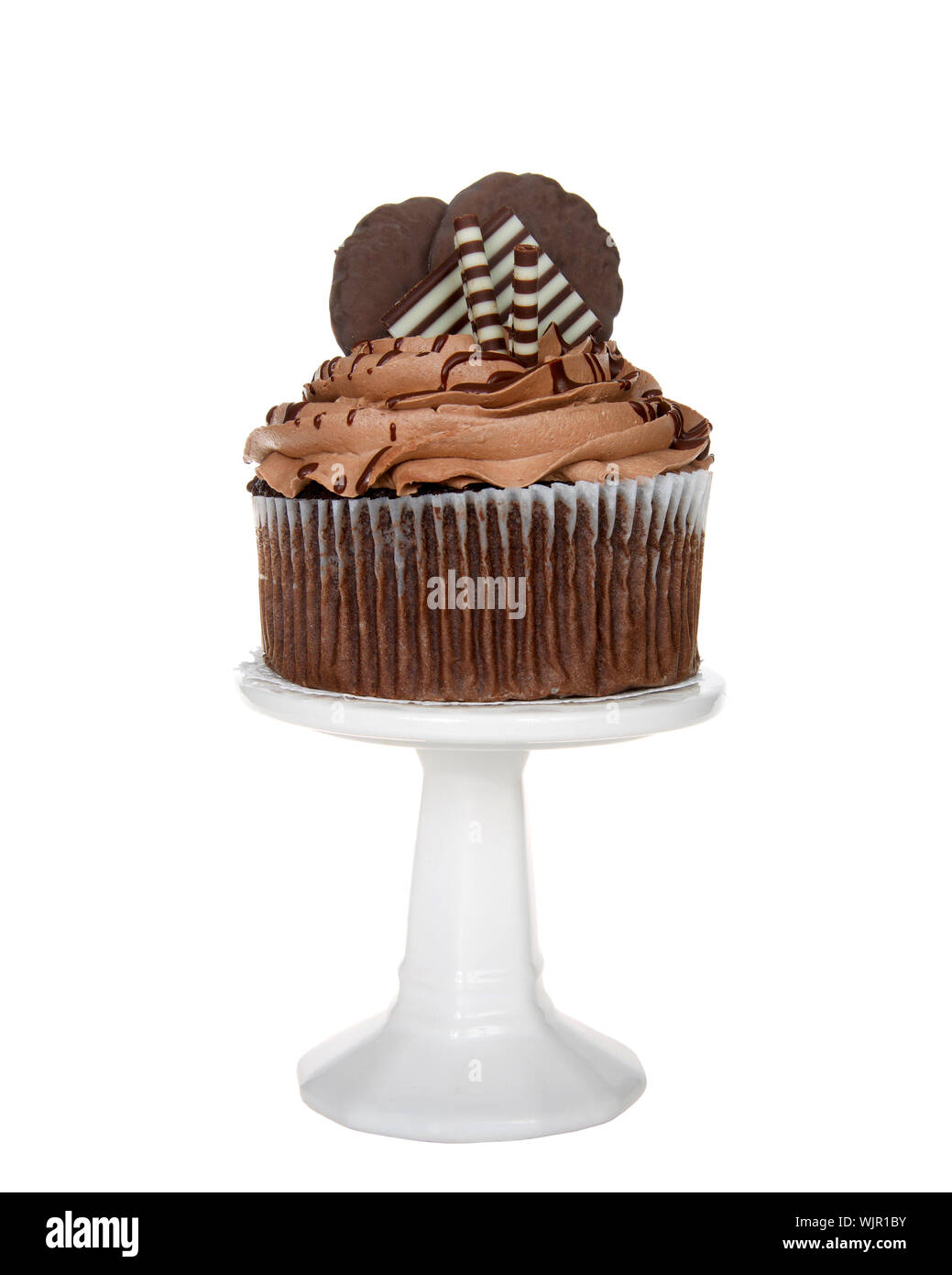 Giant chocolate cup cake with chocolate frosting, candy and cookies embellishing sitting on a white pedestal isolated on white. Stock Photo
