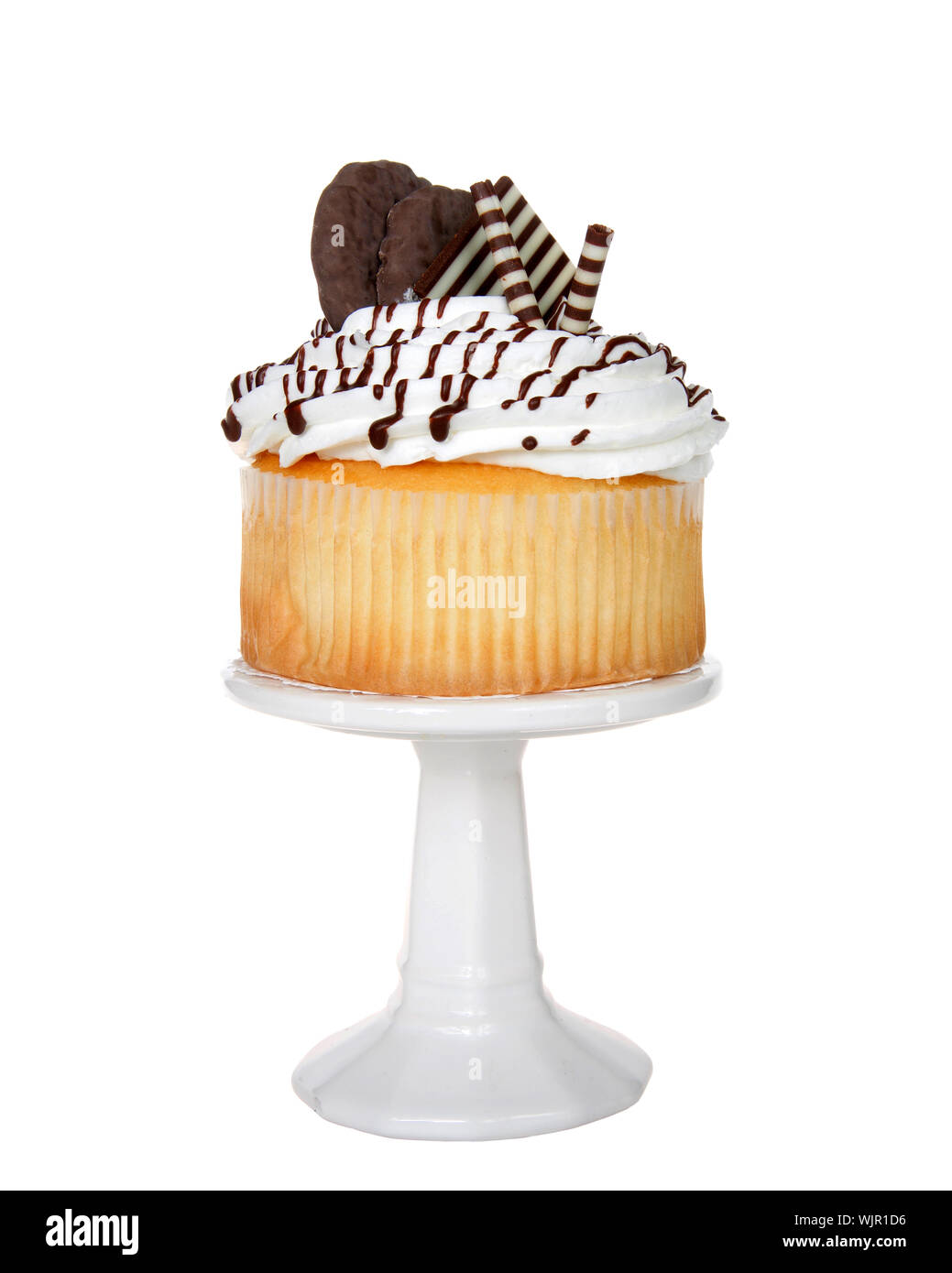 Giant vanilla cup cake with white frosting, chocolate candy and chocolate cookies embellishing sitting on a white pedestal isolated on white. Stock Photo