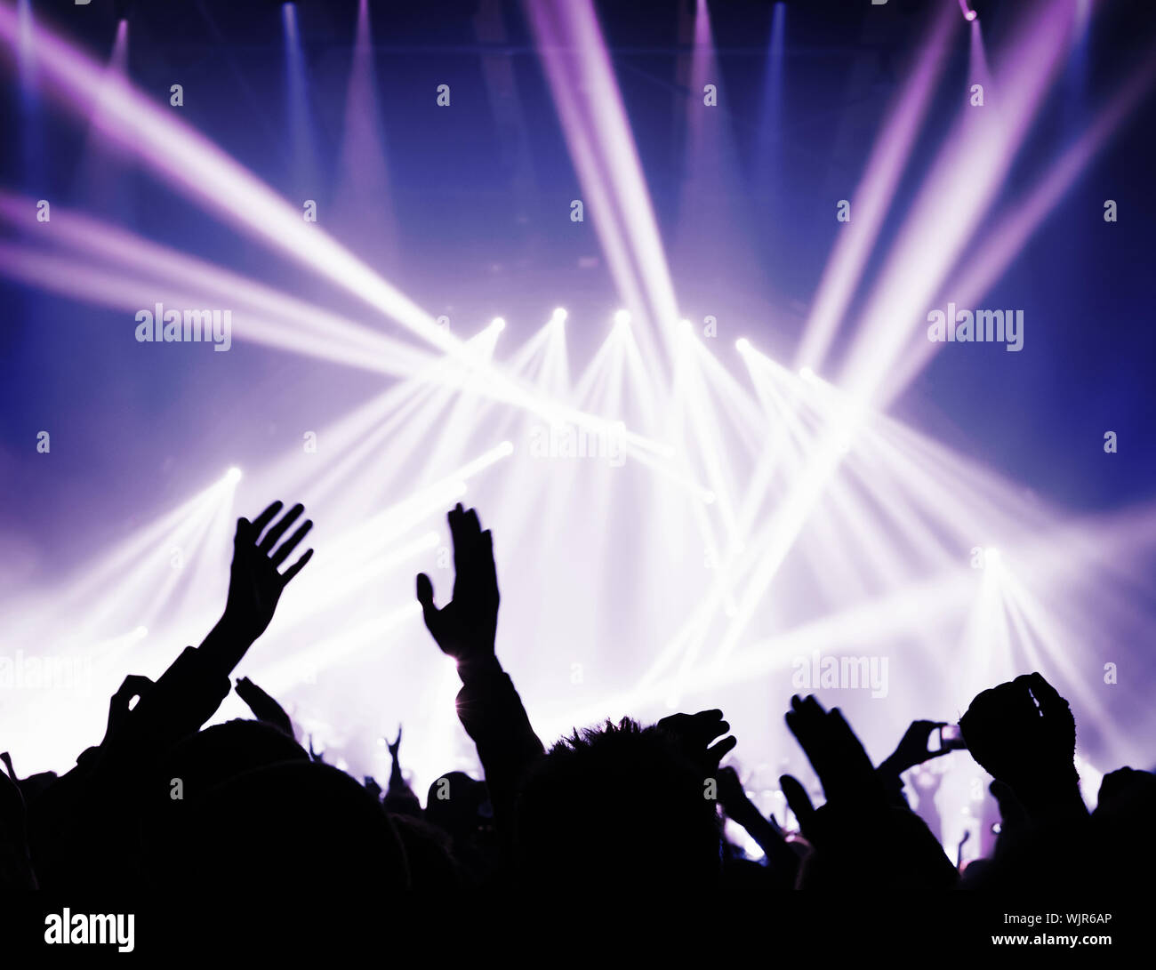 Music concert, silhouette of raised up people hands in bright blue