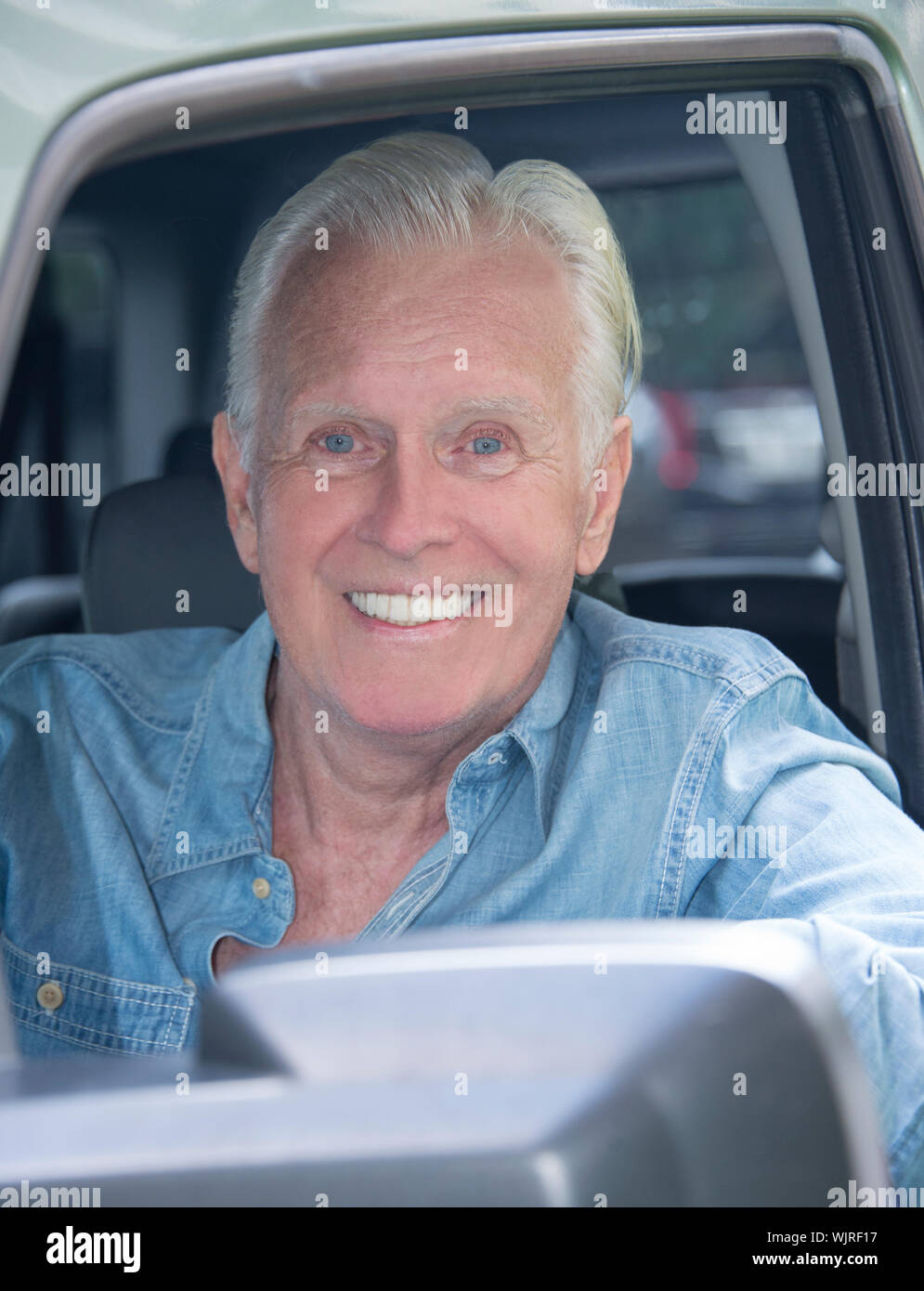 An Attractive Happy Senior Caucasian Man 70-79 age Head Shot in a Car Window Smilling at the Camera with White Hair and is Released. Stock Photo