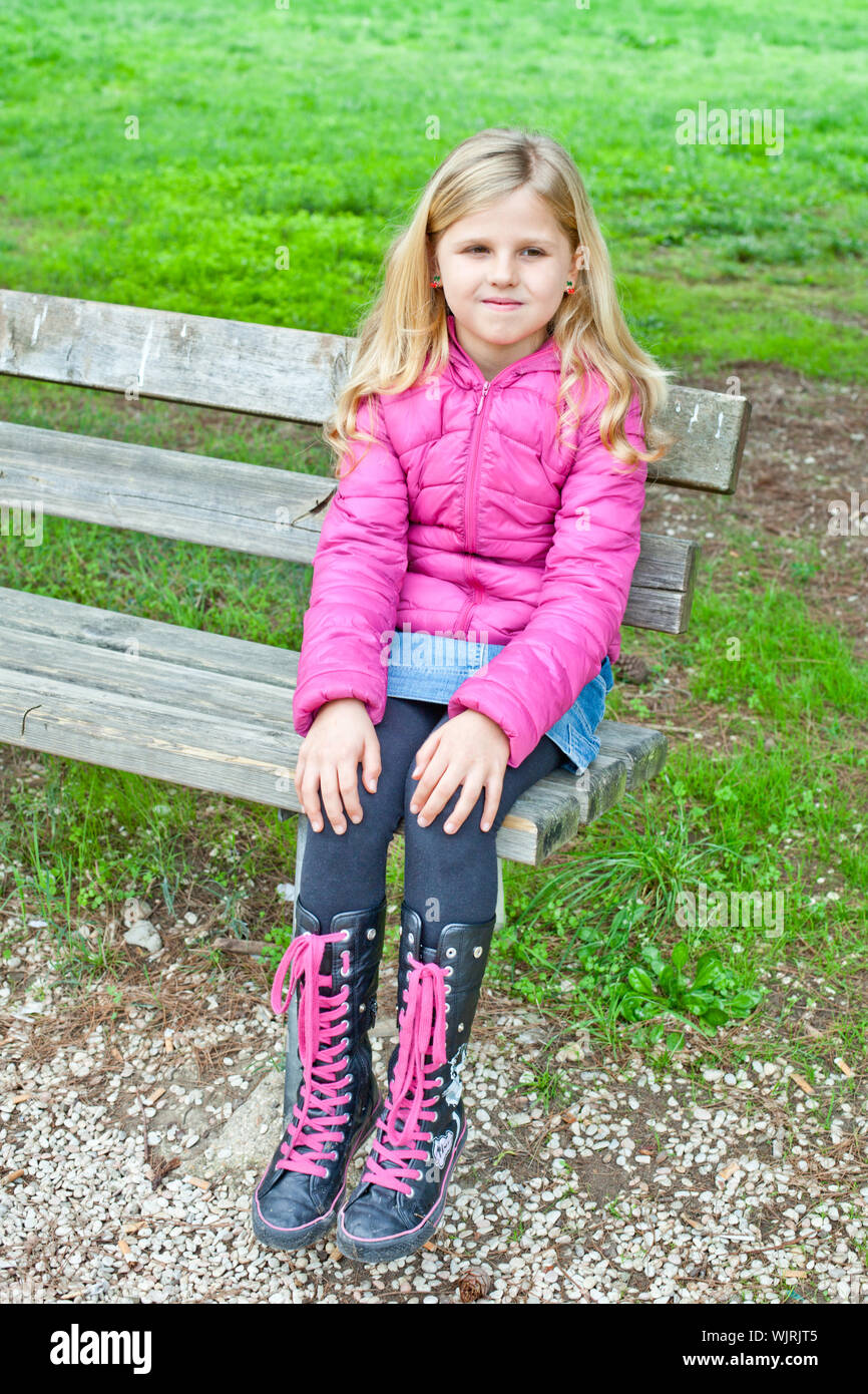 pretty little girl sitting on a bench in the park Stock Photo - Alamy