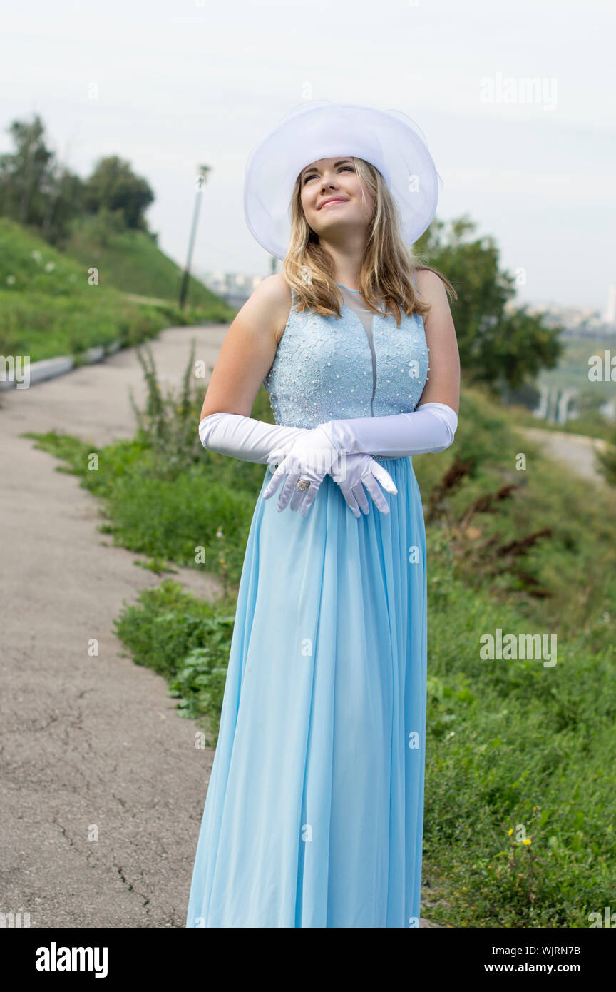 Young girl in white hat, white gloves and a blue dress. Stock Photo