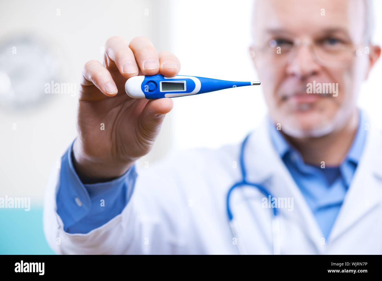 Senior doctor with thermometer measuring and showing temperature Stock