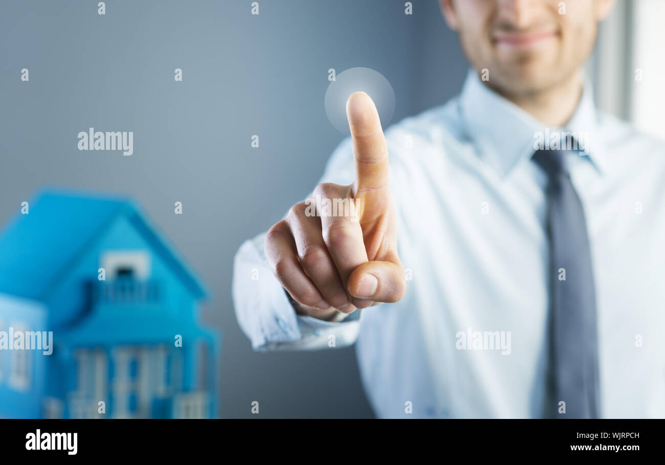 Man using touch screen interface with model house on background. Stock Photo