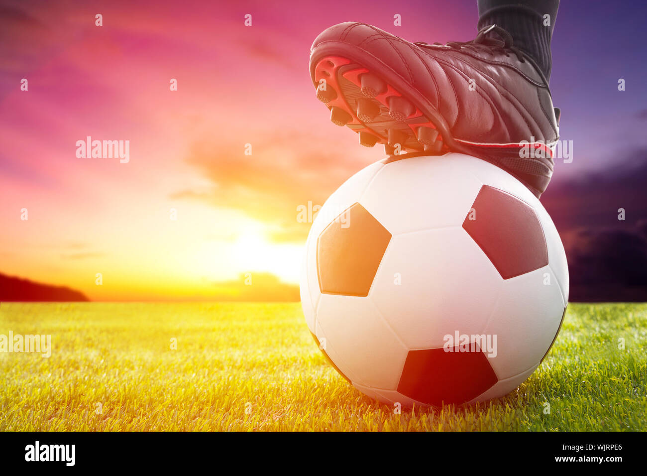 Football or soccer ball at the kickoff of a game with sunset Stock