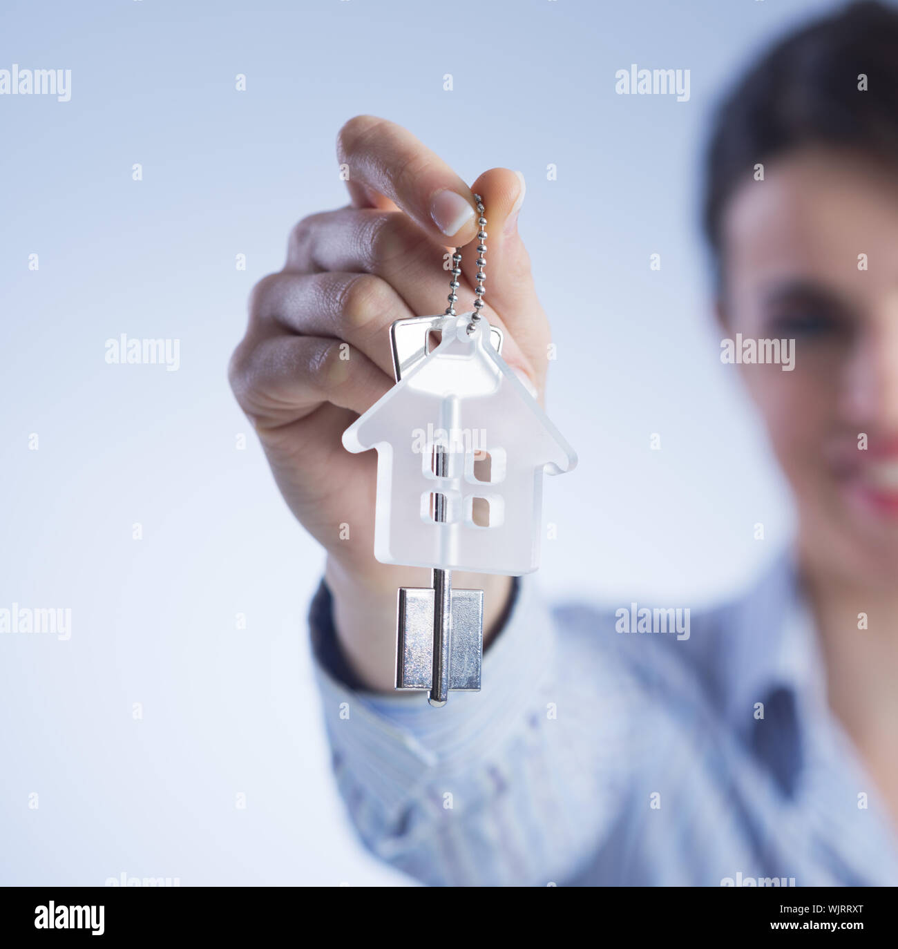 Real estate agent holding out house keys and smiling Stock Photo - Alamy