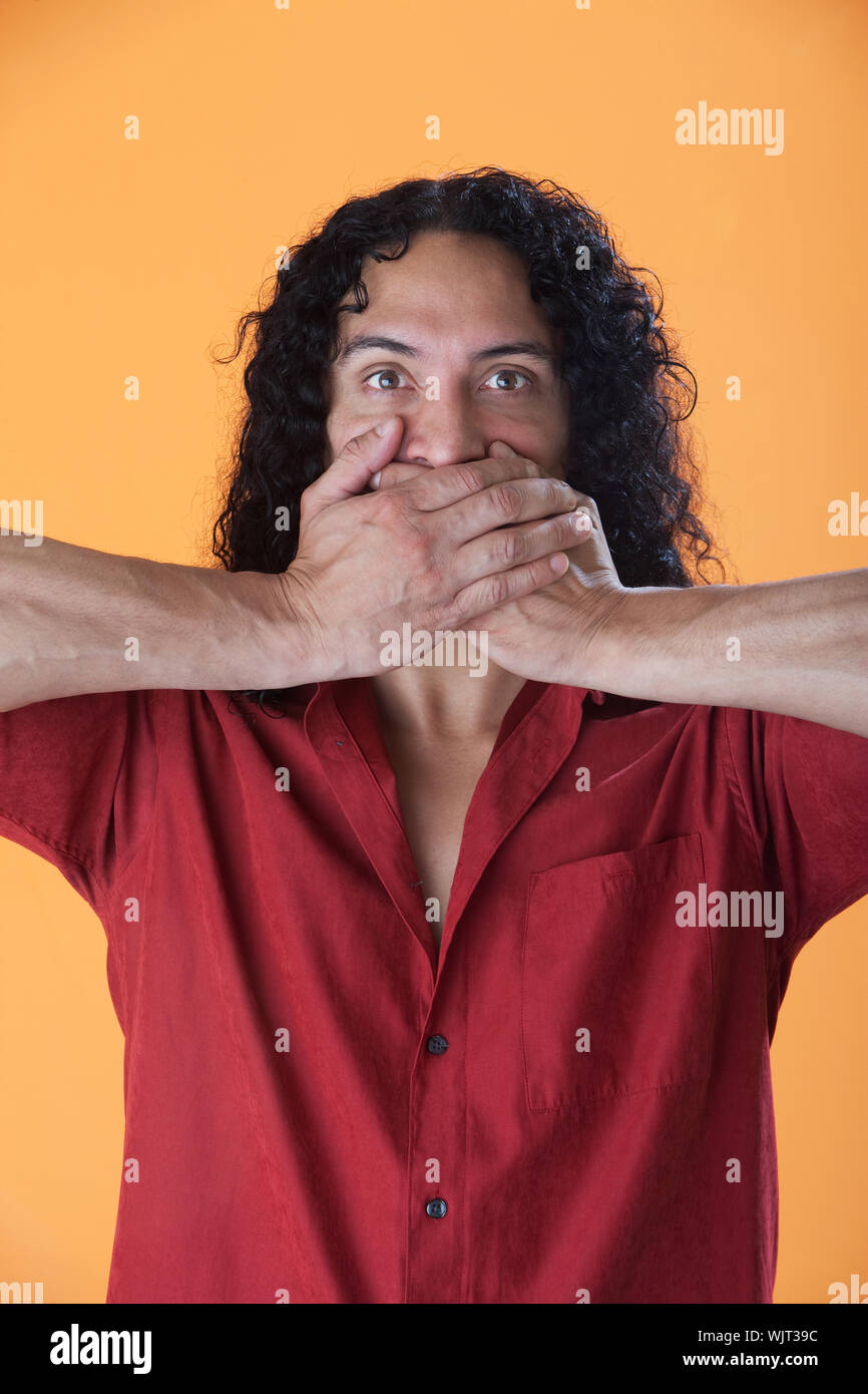 Handsome curly haired man covering his mouth with his hands Stock Photo