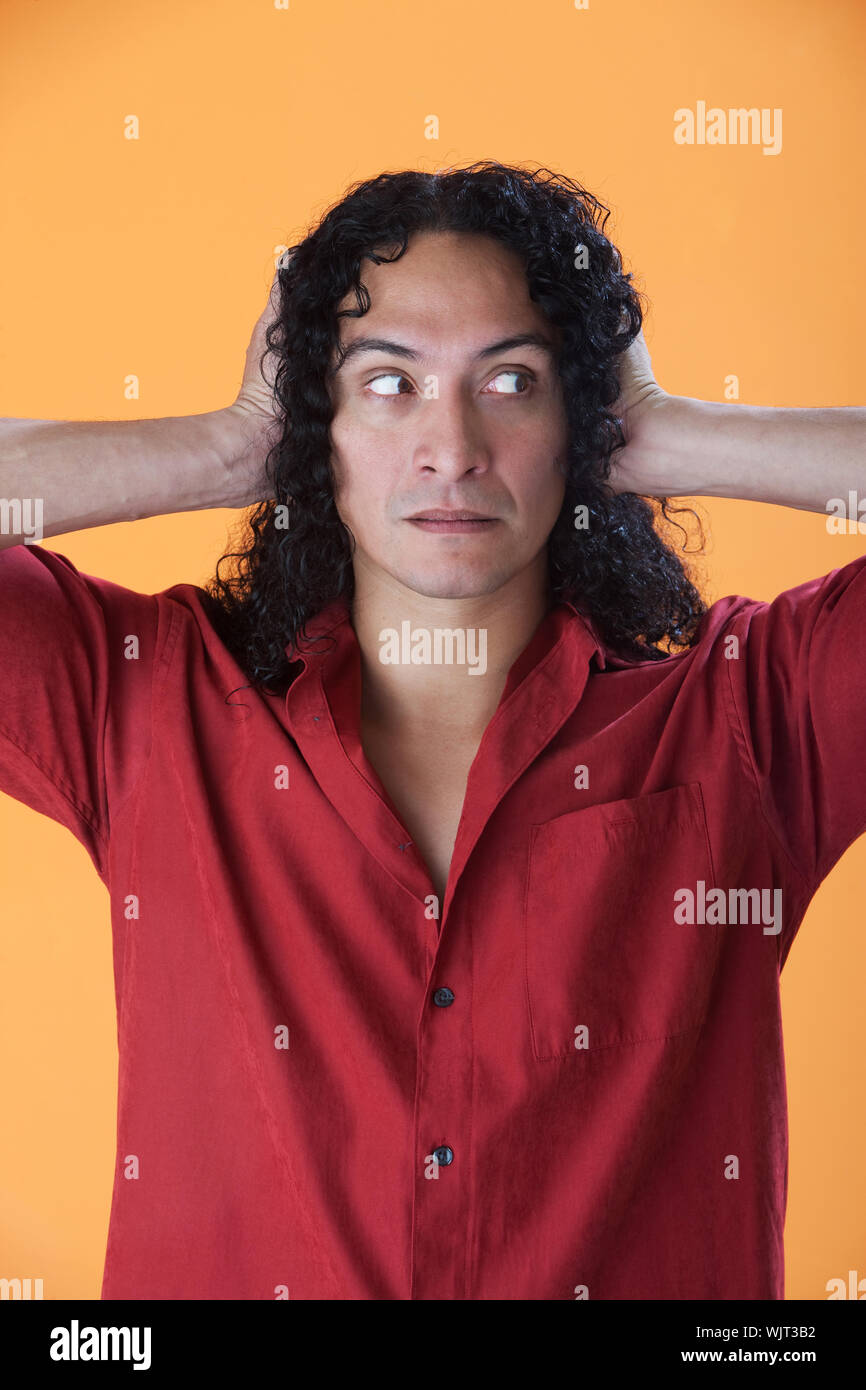 Handsome curly haired man covering his ears with his hands Stock Photo