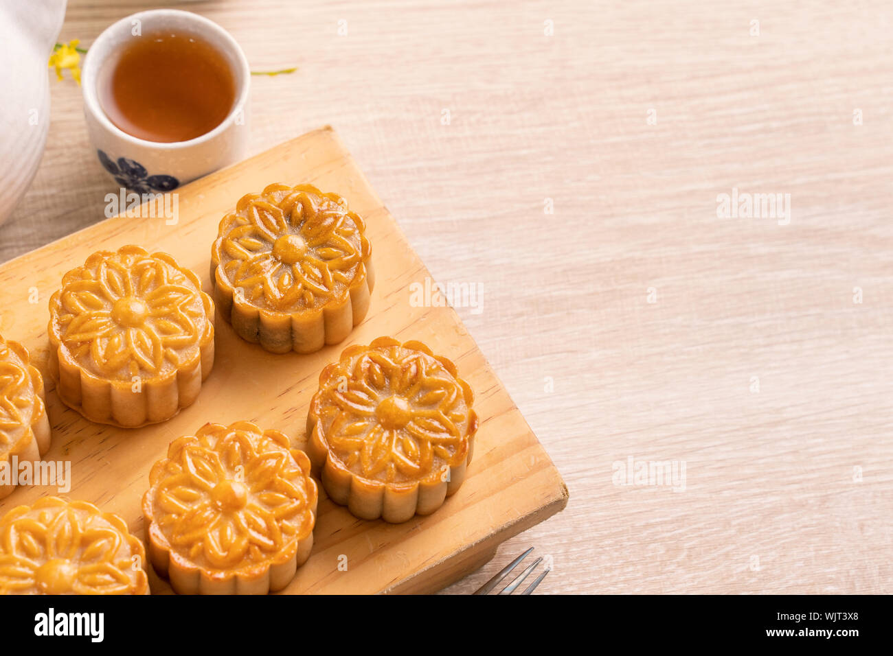 Moon cakes with tea on bright wooden table and serving try, holiday concept of Mid-Autumn festival traditional food layout design, close up, copy spac Stock Photo