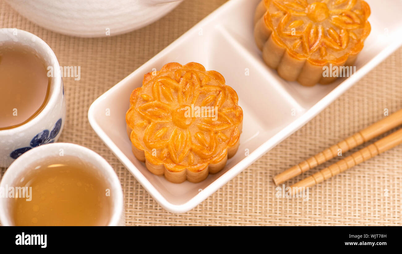 Moon cakes with tea on bright wooden table and serving try, holiday concept of Mid-Autumn festival traditional food layout design, close up, copy spac Stock Photo