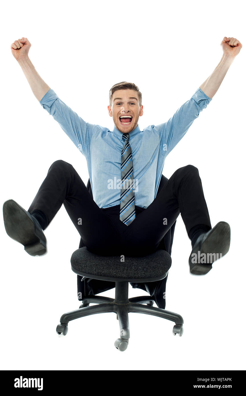 Excited business man with arms raised while sitting Stock Photo - Alamy