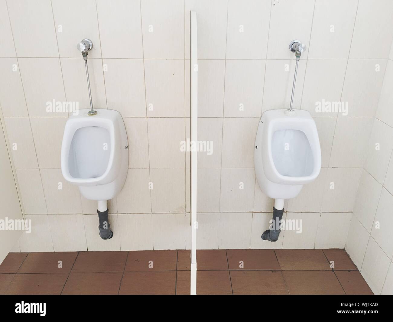 Flushing Toilets Against Tile Wall In Bathroom Stock Photo