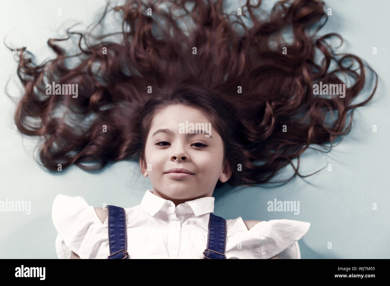 Girl With Long Healthy Brunette Hair On Blue Background Little
