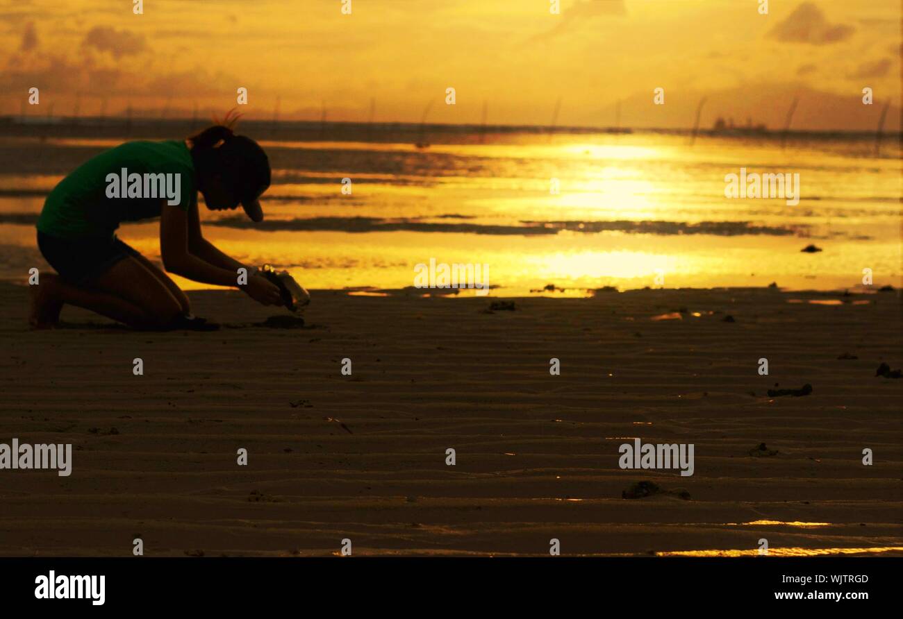 Woman kneeling sand beach sunset beach hi-res stock photography and ...