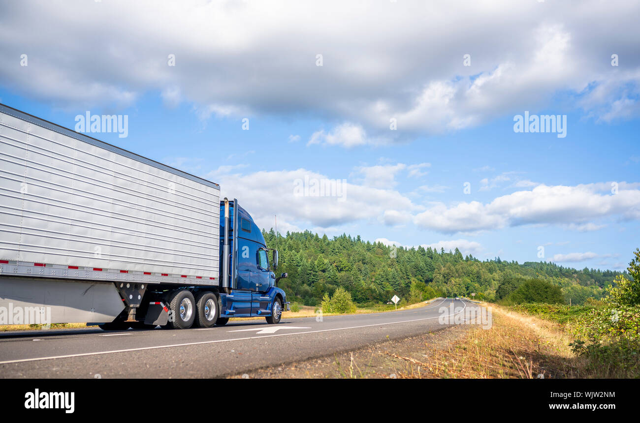 Big rig powerful professional industrial blue bonnet semi truck for long haul delivery commercial cargo going with refrigerator semi trailer on the su Stock Photo