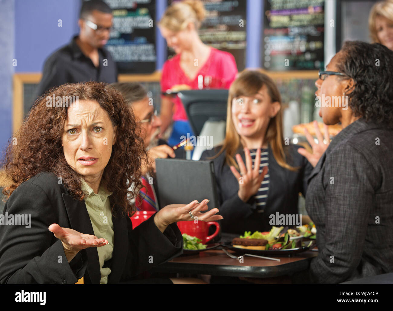 Irritated business woman with coworkers in cafeteria Stock Photo