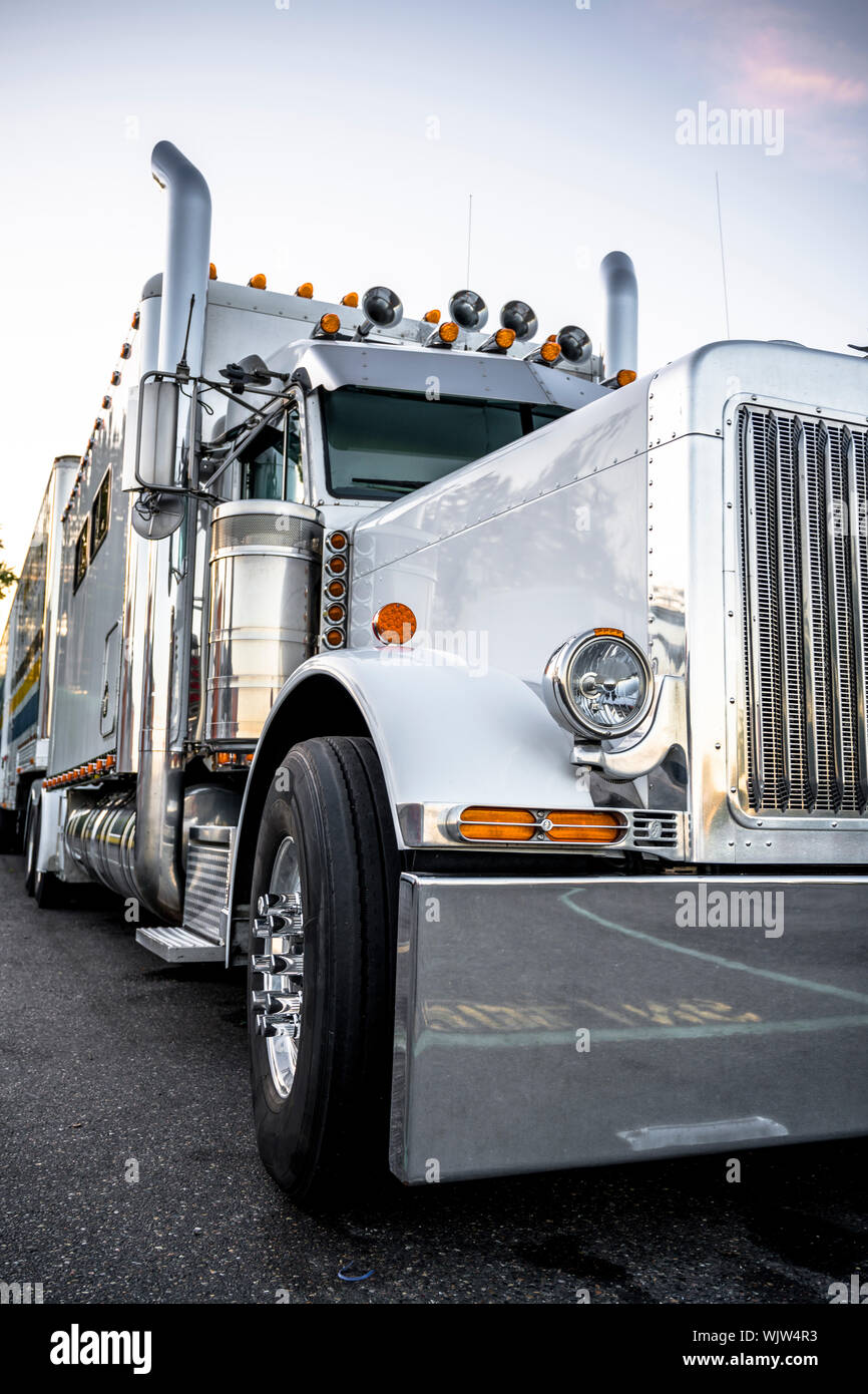 Industrial Grade Black Classic Shiny Big Rig Semi Truck Tractor With Chrome  Accessories And Massive Grille Guard And Flat Bed Semi Trailer Standing On  The Truck Stop Parking Lot For Truck Driver