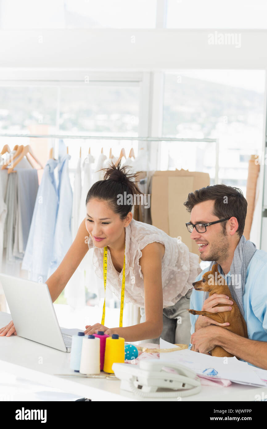 Male and female fashion designers using laptop at work in a studio ...
